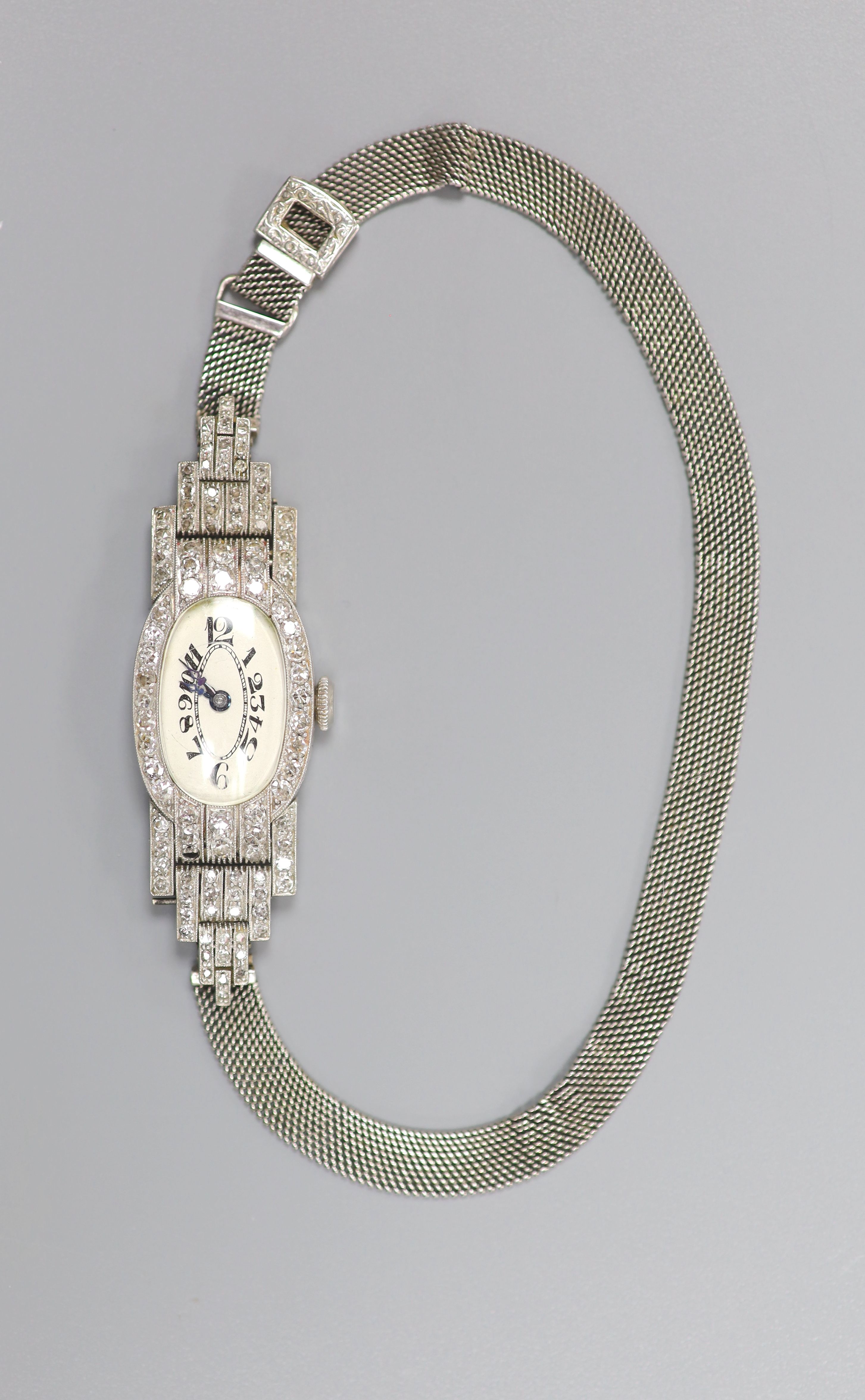 A lady's mid 20th century white metal (stamped platinum) and diamond set cocktail watch, with tumbling numerals, on an 18ct mesh link strap